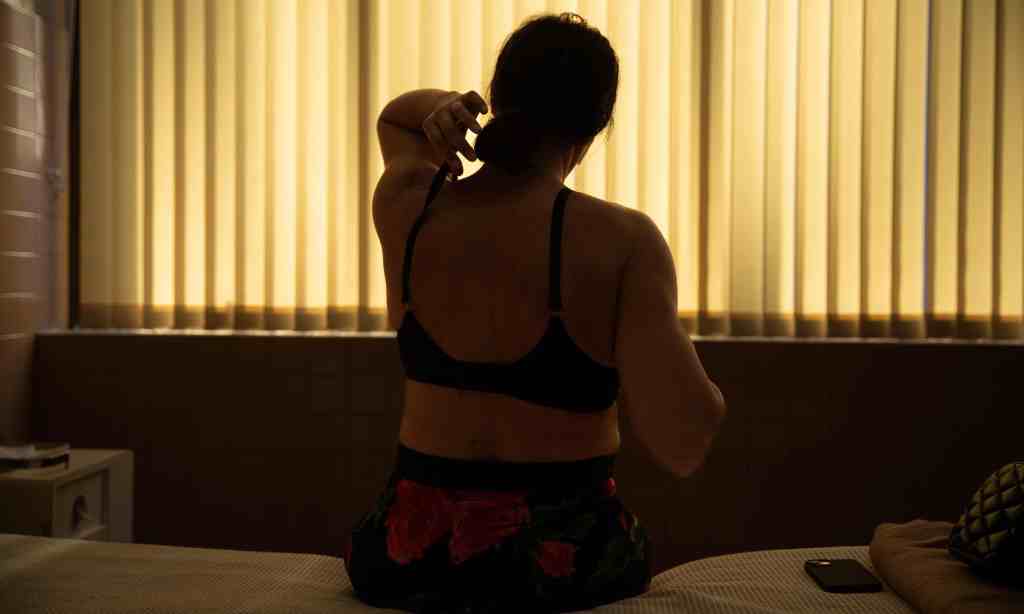 Film still of Emilia Perez, a woman with her back to the camera adjusting her bra