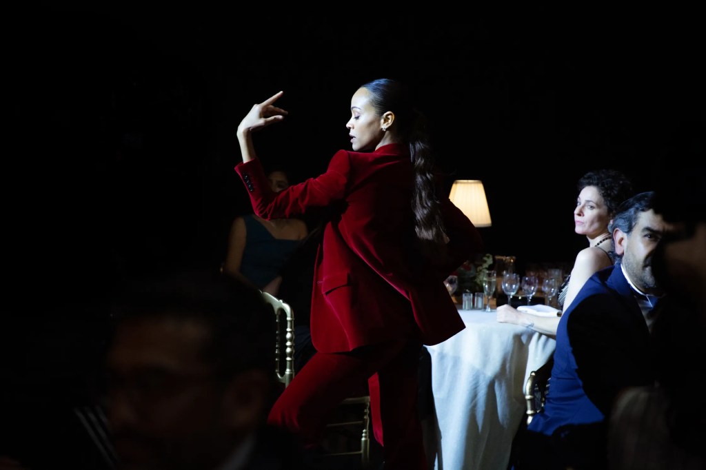 Zoe Saldaña dancing in Emilia Perez in a red velvet suit