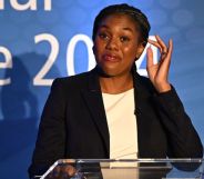 This is an image of UK government minister Kemi Badenoch. She is speaking at an event. She is wearing a black blazer and white top and has a look of confusion in her face.