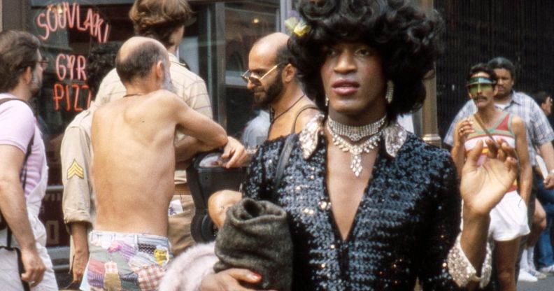 Marsha P Johnson photographed walking through a busy street.