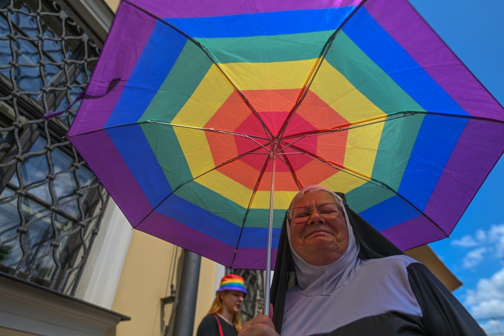 A woman dressed as a clergywomen with rainbow umbrella
