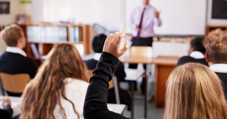 A person raising their hand in a classroom.