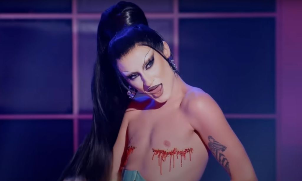 Drag Race star Gottmik with glitter covering her top surgery scars during a lip-sync.