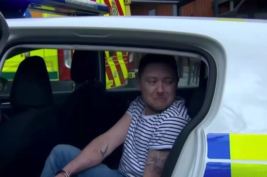 Image shows Matty Barton (Ash Palmisciano) in a police car