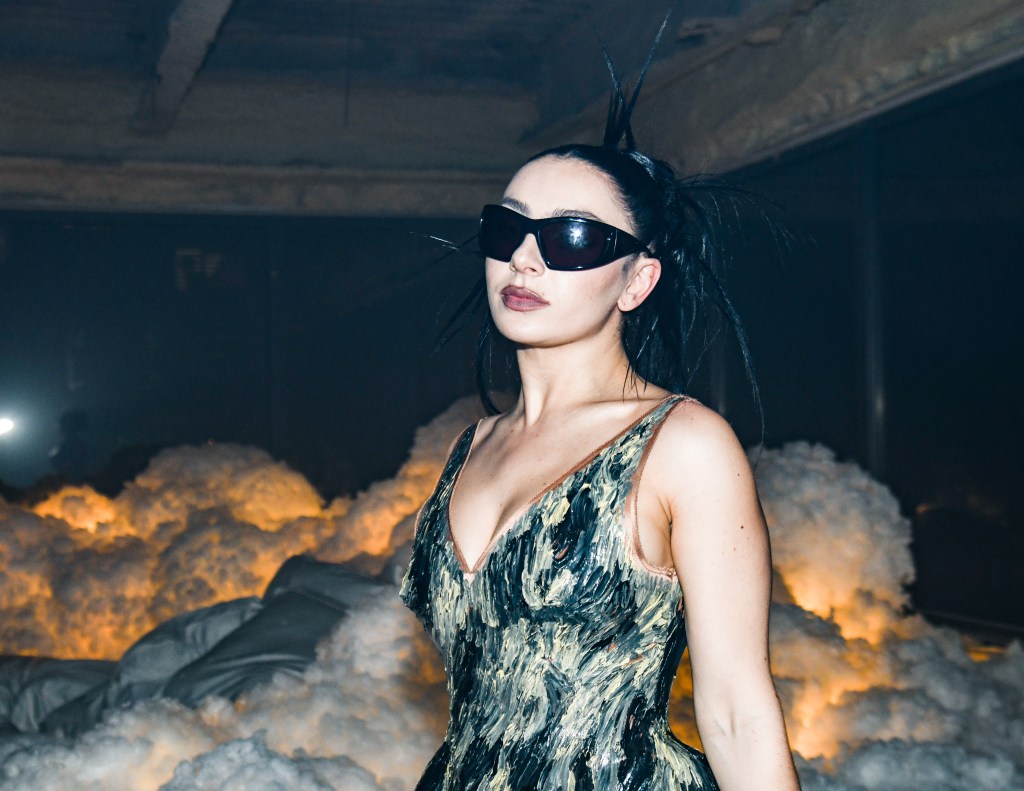 Charli XCX at the Après Met 2 Met Gala After Party, wearing sunglasses in a room that is full of cloud-looking art on the floor.