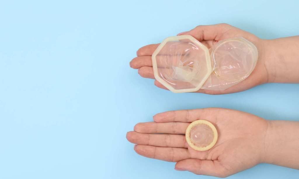 A pair of hands holding an unwrapped condom