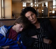 Crossing still: a teenage boy asleep on an older woman's shoulder
