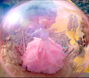 Photo shows Ariana Grande as Glinda The Good Witch floating in a pink bubble wearing a pink dress and holding a wand