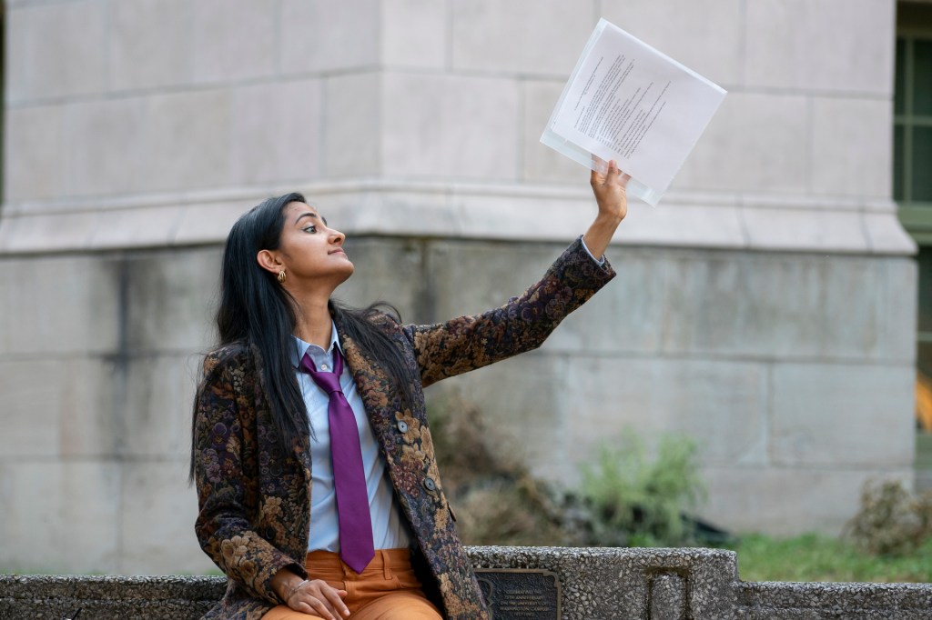 The Sex Lives of College Girls' Amrit Kaur as Bela in a suit waving papers over her head