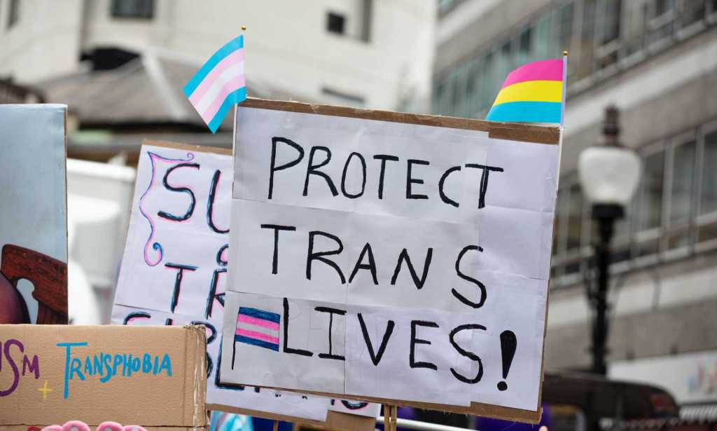 a sign reading 'protect trans lives'