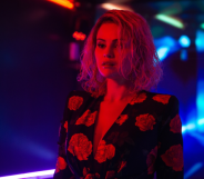 Emilia Perez film still, selena gomez in a floral dress bathed in red light