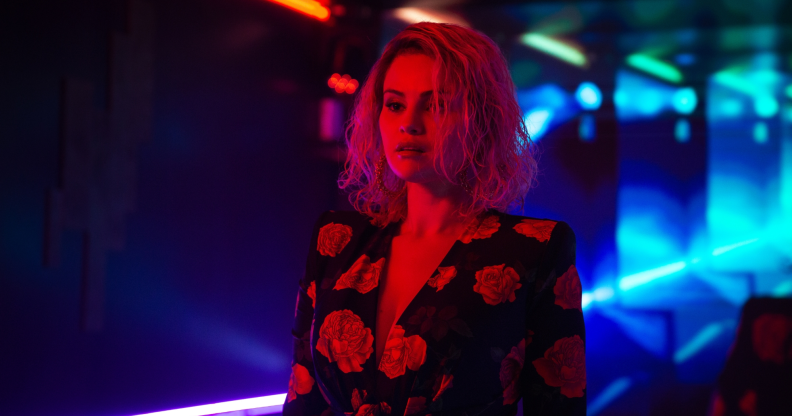 Emilia Perez film still, selena gomez in a floral dress bathed in red light