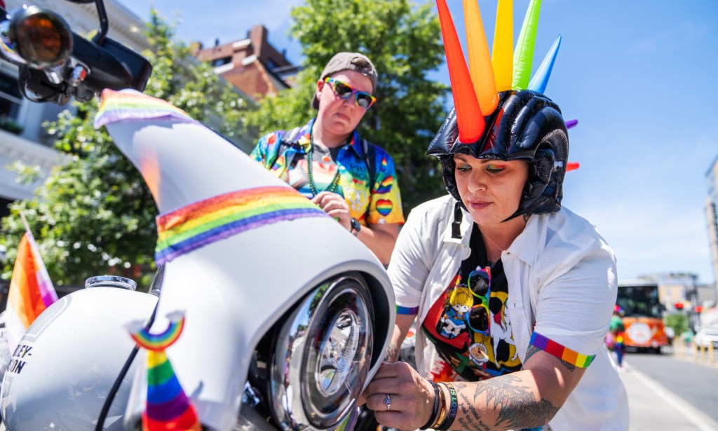 A person operating a Pride themed Harley-Davidson