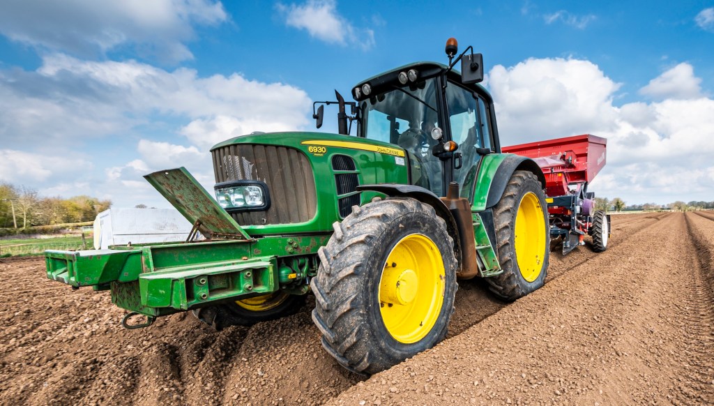 Mechanised planting of seed potatoes using a dewulf 3 row belt planter behind a John Deere tractor.