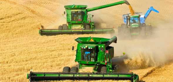 Agriculture - Two John Deere combines in tandem harvest wheat while one unloads into a grain cart. (Photo by: Rick Dalton /Design Pics Editorial/Universal Images Group via Getty Images)