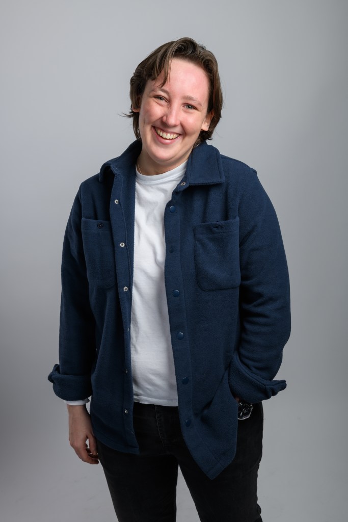 Mhairi Black: Politics Isn’t For Me at Edinburgh Fringe. Mhairi is smiling at the camera, wearing a white t shirt and a dark navy button up jacket.