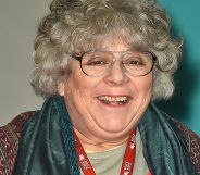 Miriam Margolyes, pictured in a pair of glasses, a scarf, and a brown top.