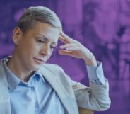 This is an image of an LGBTQ+ professional looking depressed or stressed. She is wearing a khaki suit.