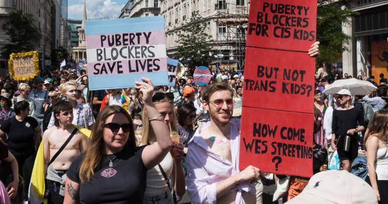 Protestors holding up signs in favour of puberty blockers.