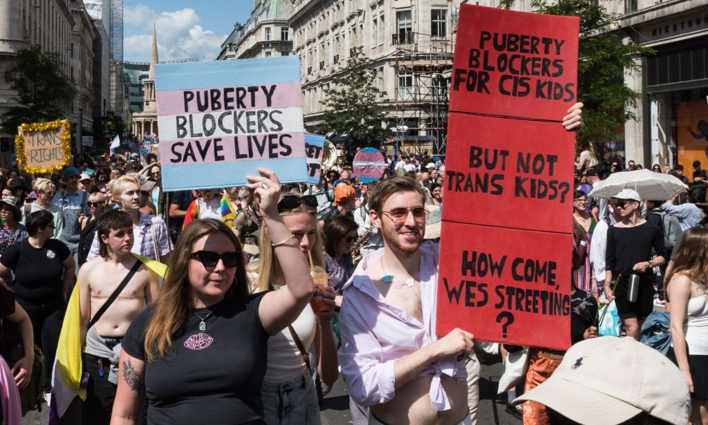 Protestors holding up signs in favour of puberty blockers.