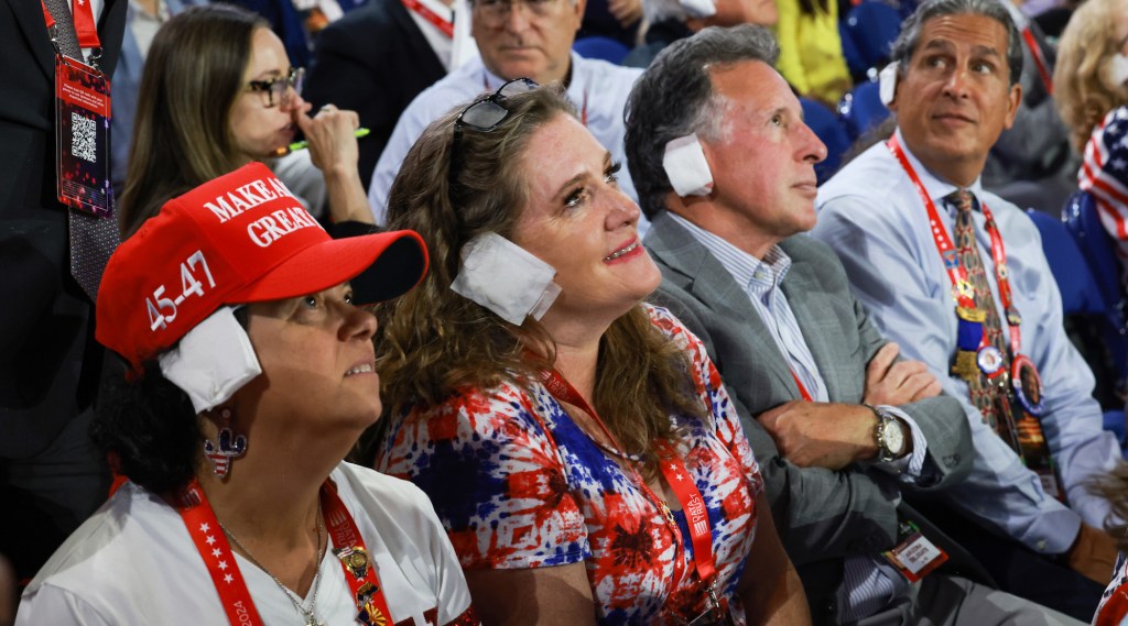 MILWAUKEE, WISCONSIN - JULY 17: People wear "bandages" on their ears as they watch on the third day of the Republican National Convention at the Fiserv Forum on July 17, 2024 in Milwaukee, Wisconsin. Delegates, politicians, and the Republican faithful are in Milwaukee for the annual convention, concluding with former President Donald Trump accepting his party's presidential nomination. The RNC takes place from July 15-18. (Photo by Joe Raedle/Getty Images)