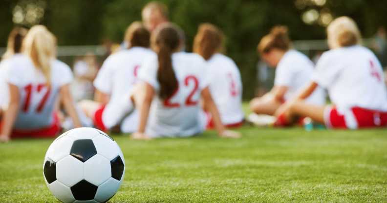 a girl's football team with football in the foreground