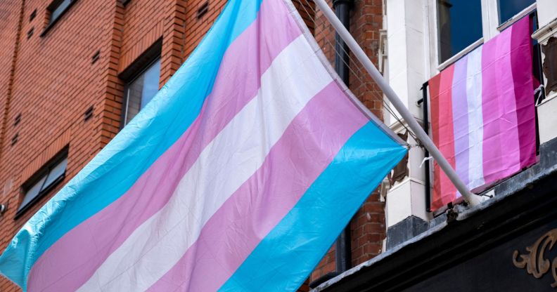 Trans flag in foreground with lesbian flag in background