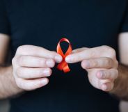 Person holding a red ribbon for HIV awareness
