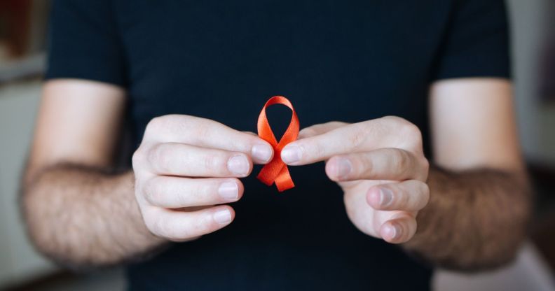 Person holding a red ribbon for HIV awareness