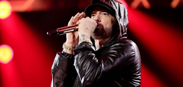 Eminem performing in a black jacket with his hood up.