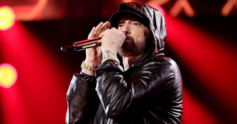 Eminem performing in a black jacket with his hood up.