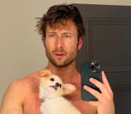 Glen Powell poses shirtless with his dog.