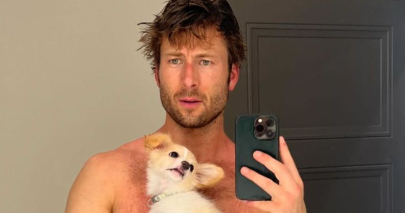 Glen Powell poses shirtless with his dog.