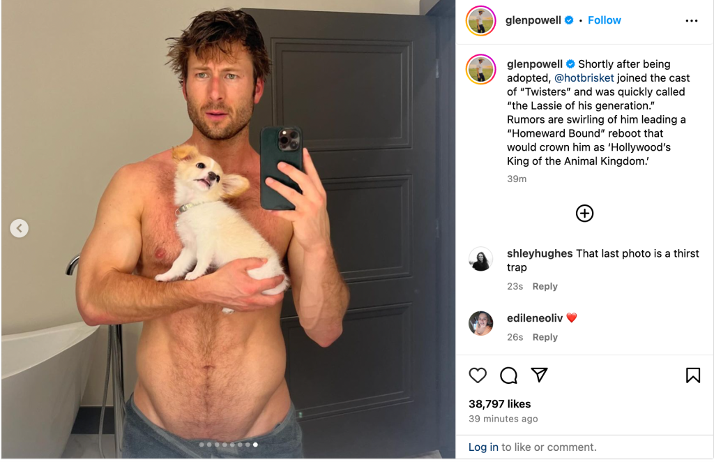 Glen Powell posts a shirtless photo on Instagram. He is holding his puppy Brisket.