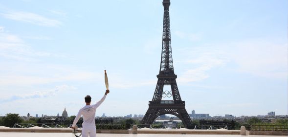 BMX rider posing with the Olympic torch in front of the Eiffel Tower ahead of the Paris Olympics Opening Ceremony
