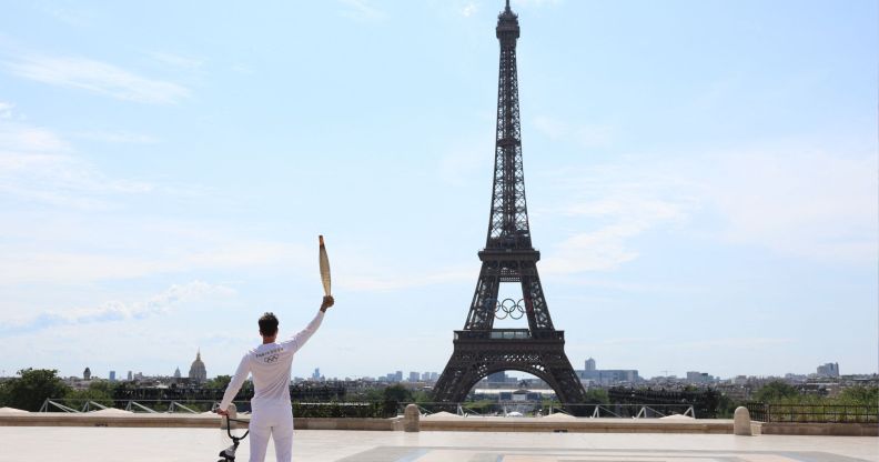 BMX rider posing with the Olympic torch in front of the Eiffel Tower ahead of the Paris Olympics Opening Ceremony