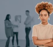 This is an image of a Black woman looking stressed and isolated at work. She has her arms crossed. In the background there are 3 other people blurred.