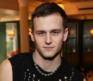 Brandon Flynn in a black tank top and chain