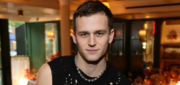 Brandon Flynn in a black tank top and chain