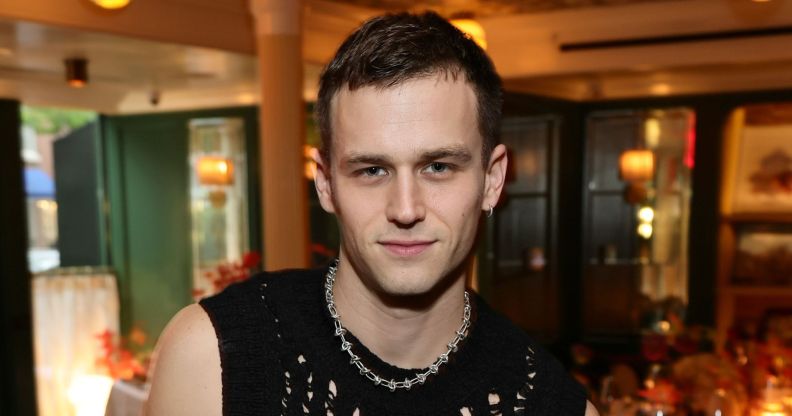 Brandon Flynn in a black tank top and chain