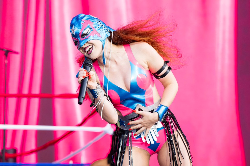 Chappell Roan performing against a bring pink background at Lollapalooza Festival, in a wrester outfit