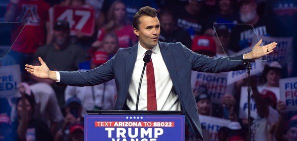 Turning Point USA Founder Charlie Kirk speaks during a campaign rally for Republican presidential nominee, former U.S. President Donald Trump, standing at the podium with his arms open