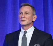 Daniel Craig in a suit and tie against a blue curtain