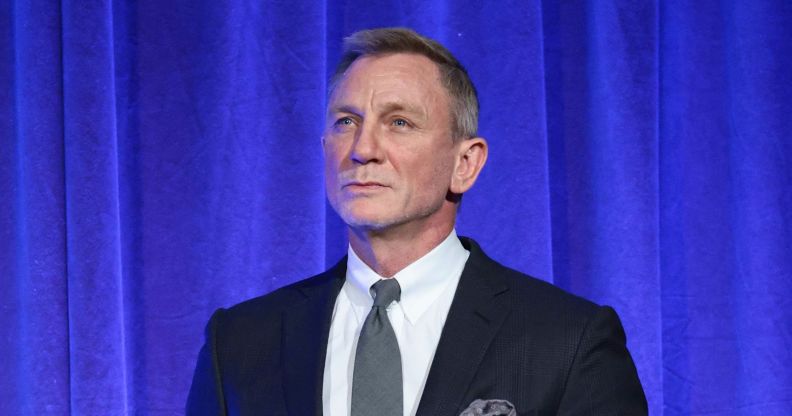 Daniel Craig in a suit and tie against a blue curtain