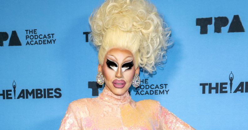 Trixie Mattel in a pink and peach gown against a blue background