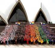 SYDNEY, AUSTRALIA - JUNE 24: 1,000 people form a human progress flag on the steps of the Opera House to mark the 44th anniversary or the Sydney Gay and Lesbian Mardis Gras Sydney Opera House on June 24, 2022 in Sydney, Australia. Australia will host WorldPride 2023. (Photo by Don Arnold/Getty Images)