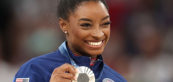 Simone Biles holding up a medal.