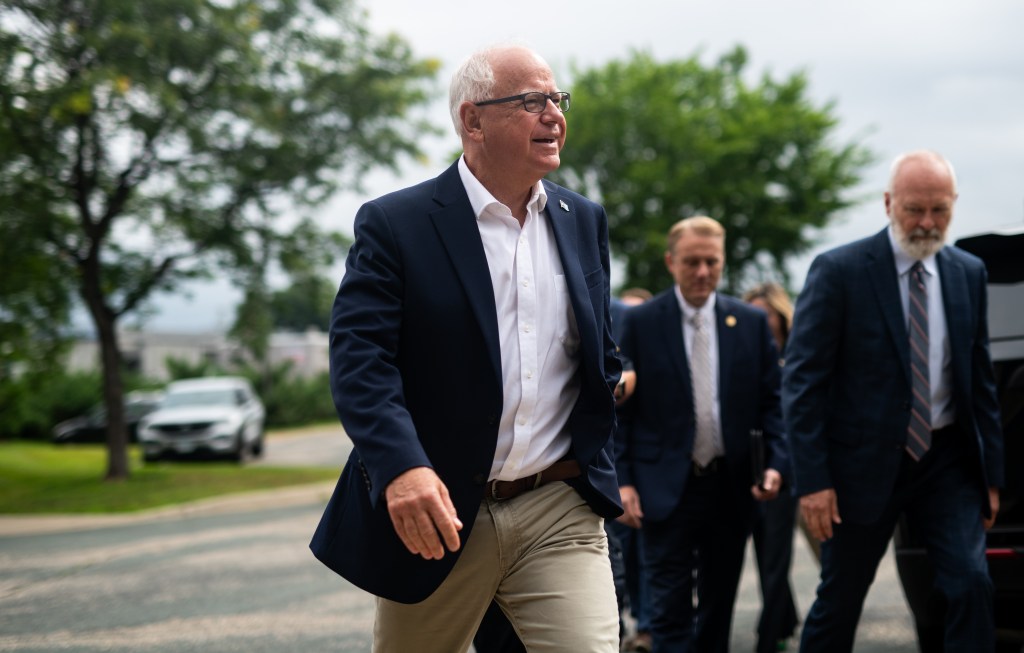 Tim Walz walking through a car park in a suit