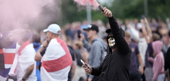 ROTHERHAM, ENGLAND - AUGUST 4: An anti-migration protester holds a flare during a riot outside of the Holiday Inn Express in Manvers, which is being used as an asylum hotel, on August 4, 2024 in Rotherham, United Kingdom. Yesterday saw widespread violence as Far-right agitators in Liverpool and Manchester rioted and looted shops. Police were attacked and injured and dozens of arrests were made. (Photo by Christopher Furlong/Getty Images)