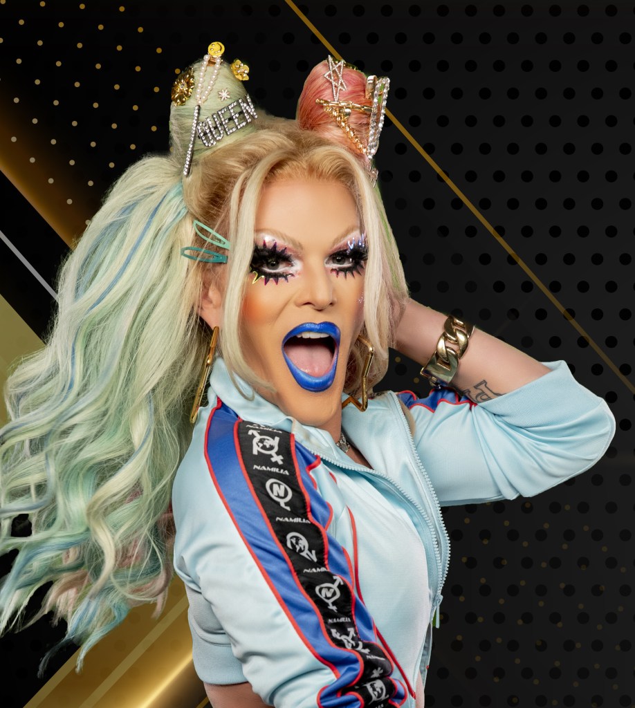 Drag Race star Willam poses with her mouth open wearing a blue jacket.